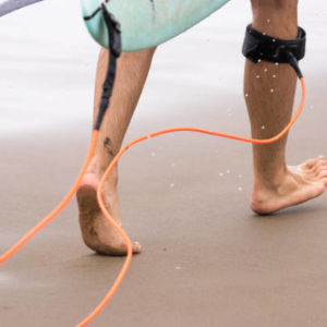 Walking surfer legs with leash and surfboard